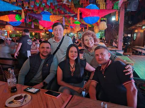       Friends seated at a busy, colorful lantern-filled restaurant.
  