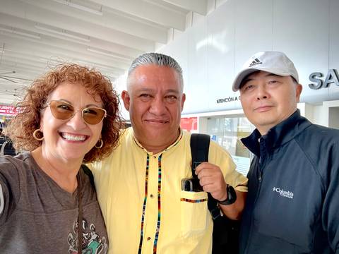       Travelers smiling for a quick photo at an airport arrivals hall.
  