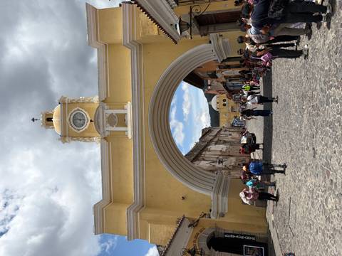       Yellow Santa Catalina Arch spanning a colonial cobblestone street in Antigua with people below.
  