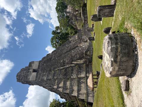       Steep pyramid temple of Tikal rising against a bright blue sky.
  