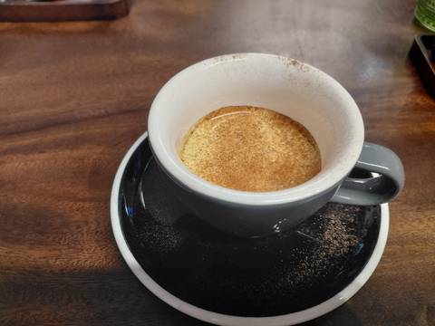      Close-up of a ceramic cup filled with creamy Vietnamese coffee on a wooden table.
  