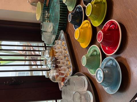      Colorful espresso cups, glasses, and tasting trays neatly arranged on a wooden counter in a café.
  