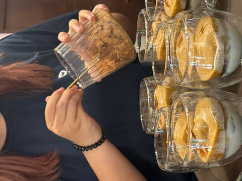       Instructor sprinkles toppings onto multiple glasses of egg coffee during a class.
  