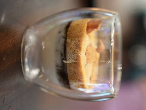       Layered egg coffee in a double-walled glass showing condensed milk, coffee and foam.
  