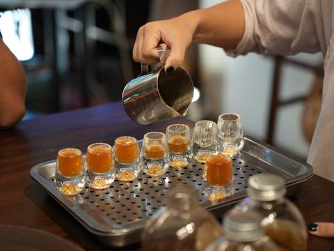       Stream of coffee poured into a neat row of tiny glasses giving off a warm hue.
  