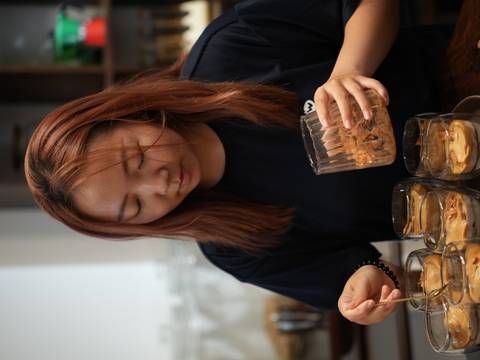       Participant carefully adding crispy flakes to glasses of egg coffee during a workshop.
  