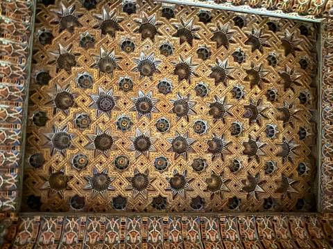       Highly detailed carved and painted wooden ceiling featuring star motifs and geometric patterns.
  