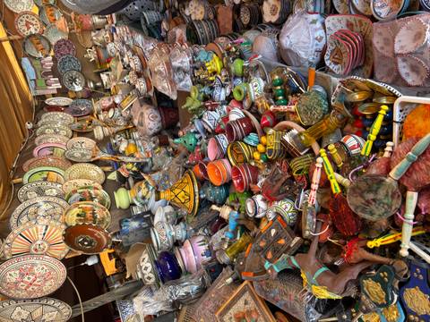       Bustling market stall overflowing with brightly painted pottery, ceramics and souvenirs.
  