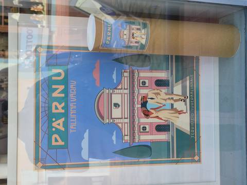       Illustrated travel poster of Pärnu displayed in a shop window along with a matching souvenir tube.
  