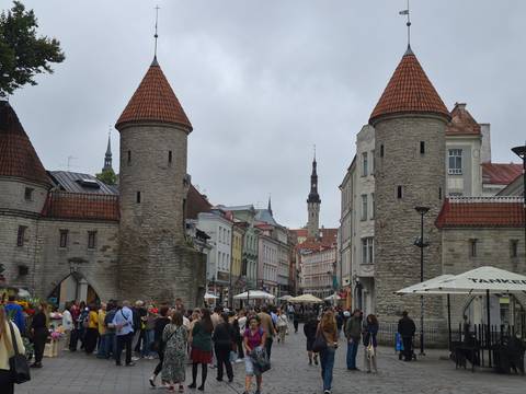       Crowds entering Tallinn’s medieval Viru Gate towers on a grey day.
  