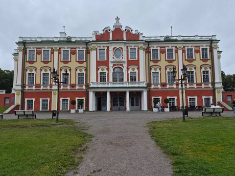       Close-up of Kadriorg Palace’s ornate red and yellow façade with visitors near the entrance.
  