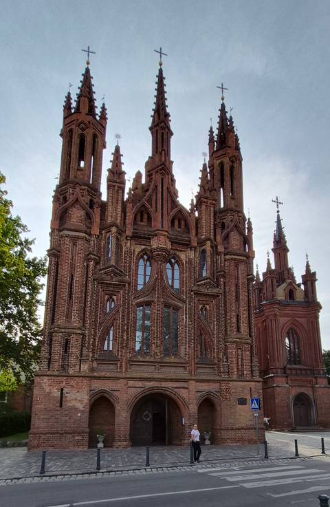       Gothic red-brick St. Anne’s Church with elaborate arches and spires captured from ground level.
  