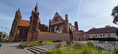       Complex of St. Anne’s and Bernardine Churches in Vilnius with red roofs and ornate brickwork under a clear sky.
  