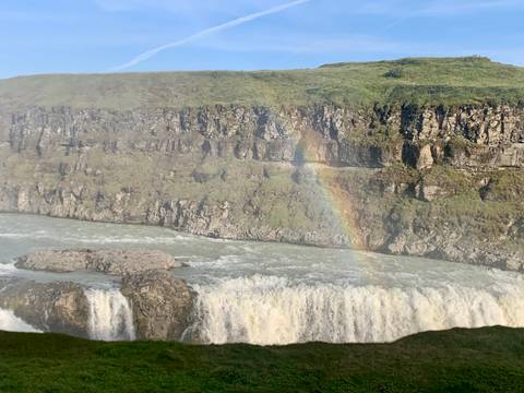       Powerful waterfall plunging into a rocky canyon with a vivid rainbow arching through the mist.
  
