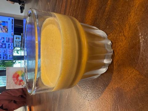       Close-up of a glass containing thick creamy Vietnamese egg coffee on a wooden table.
  