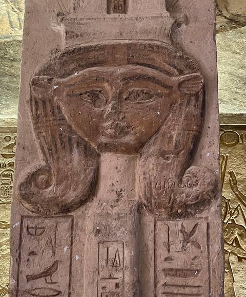       Close-up of an ancient carved relief depicting a feminine face with detailed hair.
  