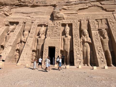       Visitors stand before the colossal statues and hieroglyphs of Abu Simbel's Great Temple.
  