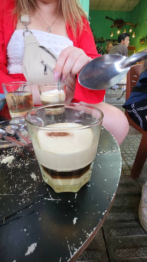       Person preparing coffee at a table with various items.
  