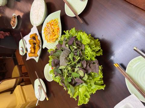       Platter of fresh lettuce and mint with other Vietnamese dishes on dark wooden table
  