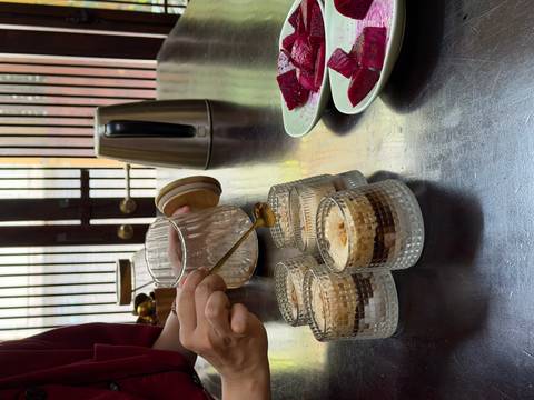       Chef drizzles syrup over layered Vietnamese egg coffee desserts beside sliced beetroot.
  