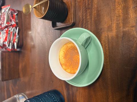       Close-up of a traditional Vietnamese egg coffee served in a mint green cup on a wooden table.
  