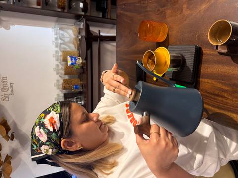       Participant carefully pouring hot water from a kettle into a Vietnamese phin filter during a coffee class.
  