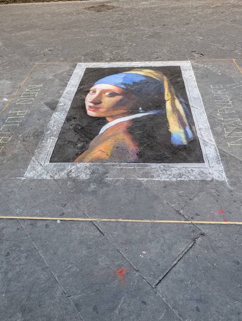       Street artist’s chalk rendition of Vermeer’s Girl with a Pearl Earring on stone pavement.
  