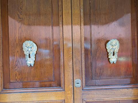       Polished wooden doors feature ornate brass lion-head keyhole plates.
  