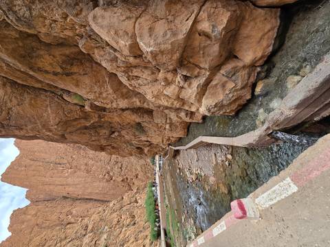      Narrow river flows through towering rust-colored walls of a rocky gorge.
  