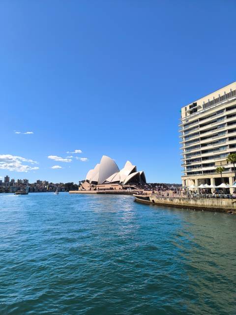       Bright view of Sydney Opera House and adjacent waterfront promenade on a clear day.
  