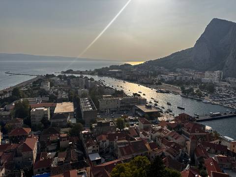       High viewpoint of a coastal town, river mouth and marina under a sunbeam and hazy sky.
  