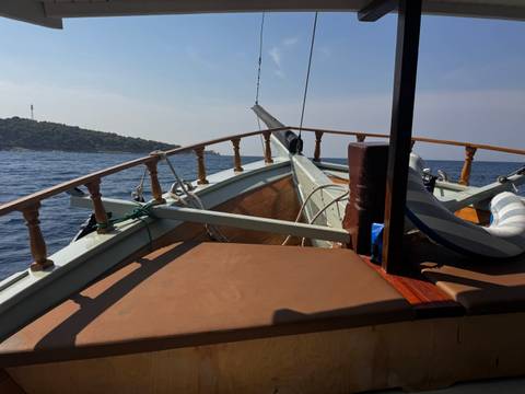       Bow of a wooden boat cutting through deep blue Adriatic waters on a clear day.
  