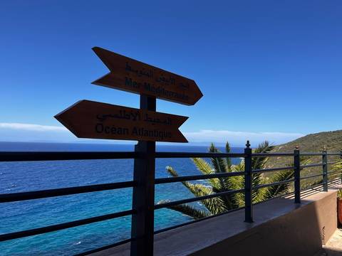       Wooden signpost shows directions to the Mediterranean Sea and Atlantic Ocean above blue water.
  