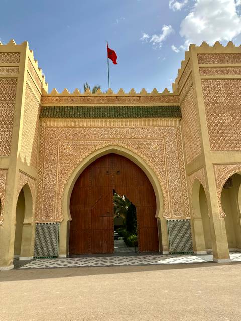       Intricately carved Moorish gateway with green tile accents and large wooden doors
  