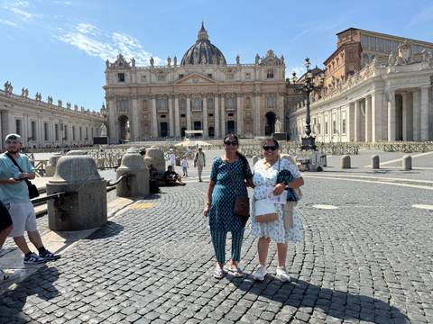       Tourists posing in St. Peter's Square with majestic basilica in background
  