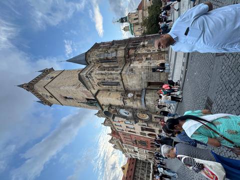       Crowds in Prague's Old Town Square with astronomical clock tower under dramatic sky
  