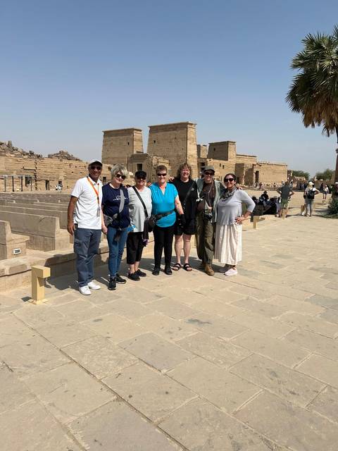       Tour group posing in front of ancient stone pylons at Philae Temple, Egypt
  