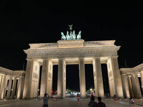       Brandenburg Gate dramatically lit at night against a dark sky.
  