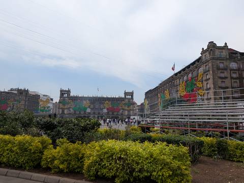       Zócalo buildings adorned with colorful Independence Day decorations beside temporary stands
  