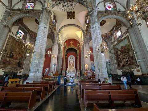       Stone columns and chandeliers inside a grand cathedral with worshippers at the altar
  