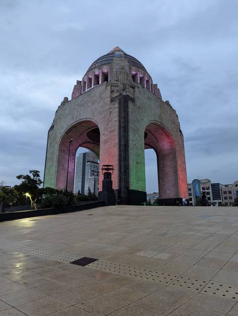       Monumento a la Revolución lit with green and red lights against an evening sky
  