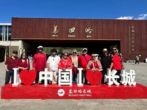       Large tour group posing behind an "I love China, I love Great Wall" sign at Mutianyu visitor center
  