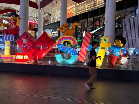       Colorful LEGO store window display spelling LOVE with a pedestrian walking past at night
  