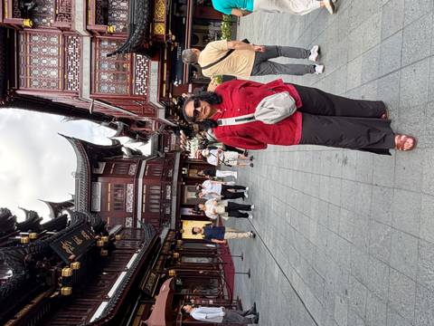       Woman standing in historic pedestrian street lined with traditional red wooden Shanghai buildings
  