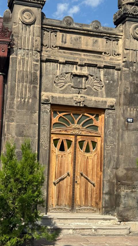       Close-up of an ornate arched wooden door set in intricately carved dark stone facade.
  