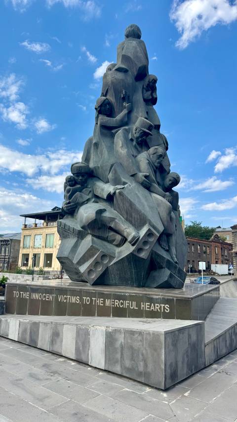       Dramatic Soviet-era stone sculpture depicting emotional human figures against a blue sky.
  