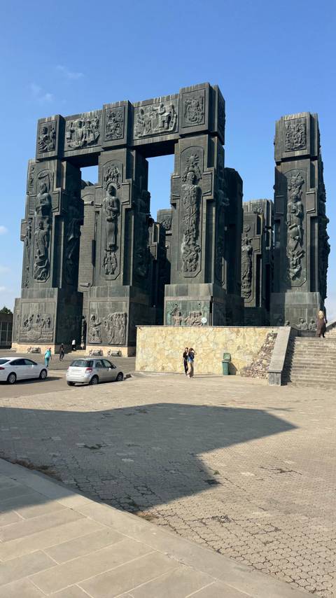       Massive dark stone pillars of the Chronicle of Georgia monument dwarf visitors at its base.
  