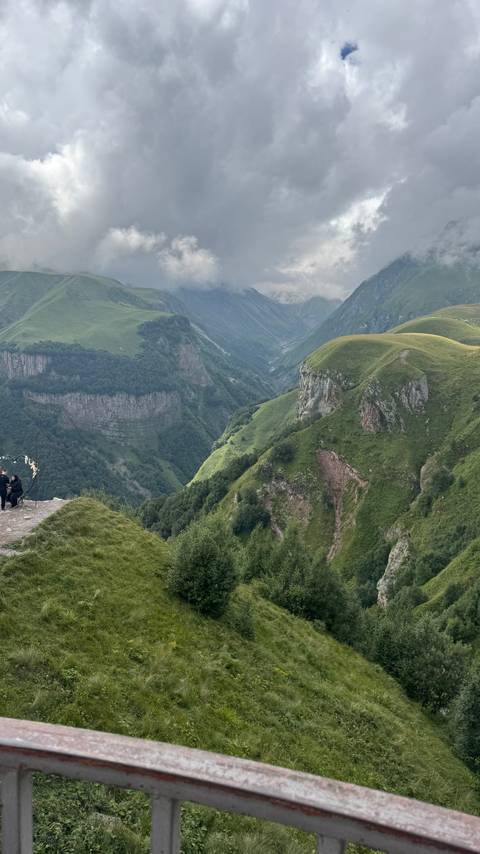       Sweeping view of deep green canyon and layered ridges under soft evening light.
  