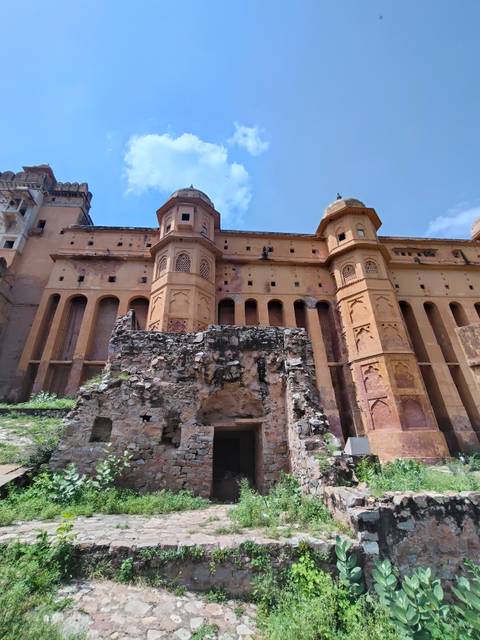       Weathered bastions and vertical windows of Amber Fort rising against a bright blue sky.
  