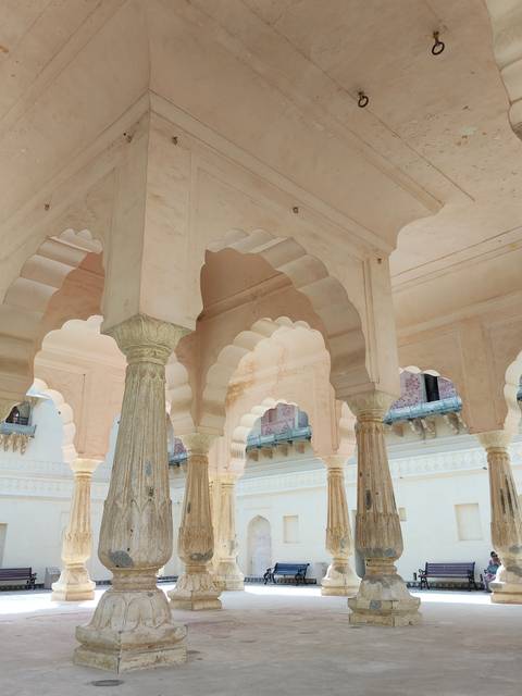       Elegant cream-colored arches and fluted pillars inside a historic palace hall.
  